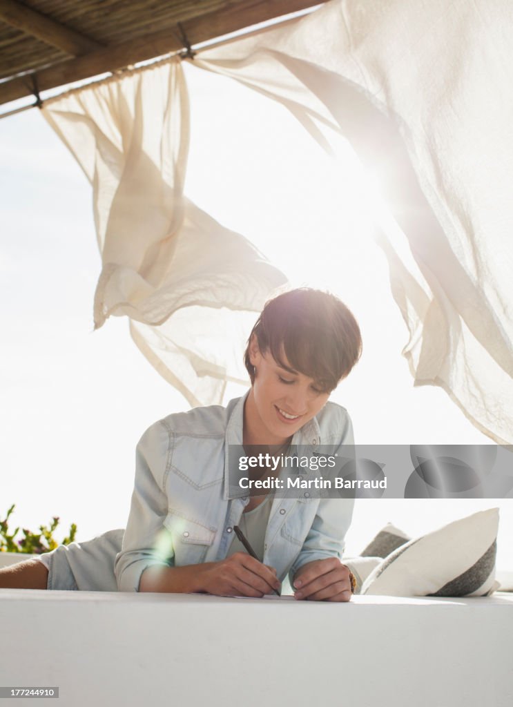Lächelnden Frau Schreiben auf der sonnigen Terrasse