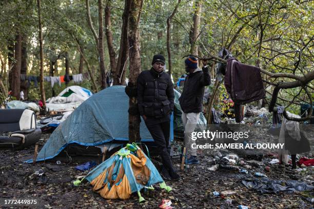 Sudanese migrants Khaled and Alaa stand next to their tents at a makeshift camp in the city of Calais, northern France on November 7, 2023. In...