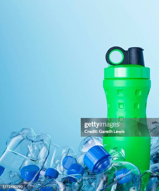 green reusable drinking bottle surround by everyday purchased water bottles 3d render - garbage pile stock illustrations
