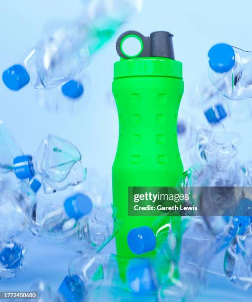 green reusable drinking bottle surround by everyday purchased water bottles 3d render - garbage pile stock illustrations