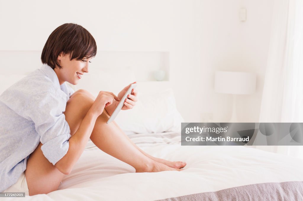 Smiling woman using digital tablet on bed