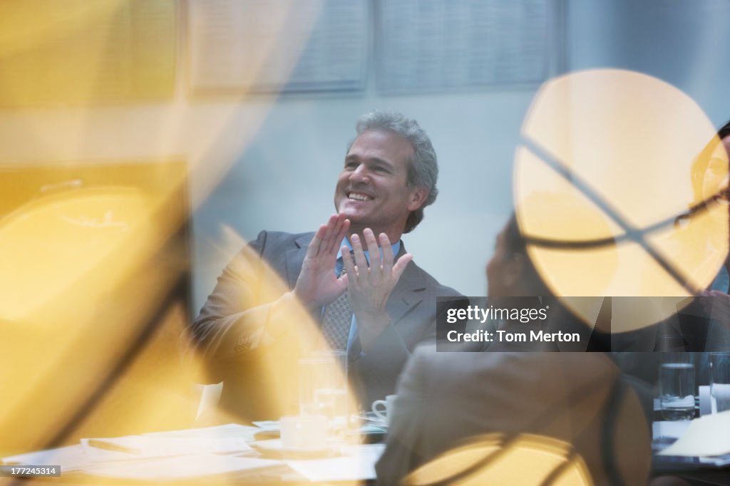 Smiling businessman clapping in meeting