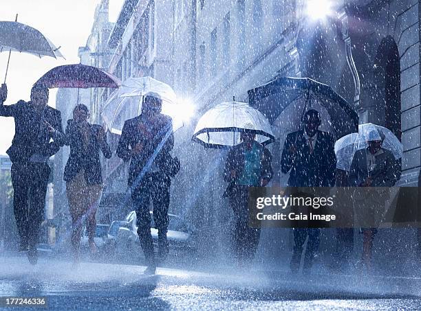 business people with umbrellas running in rain - businesswoman under stock pictures, royalty-free photos & images