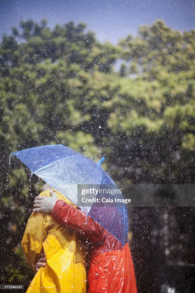 Couple hugging under umbrella in rain