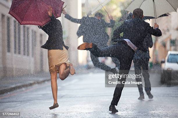 geschäftsleute mit sonnenschirmen tanz im regen - caiaimage stock-fotos und bilder