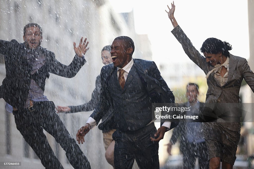 Enthusiastic business people running in rainy street