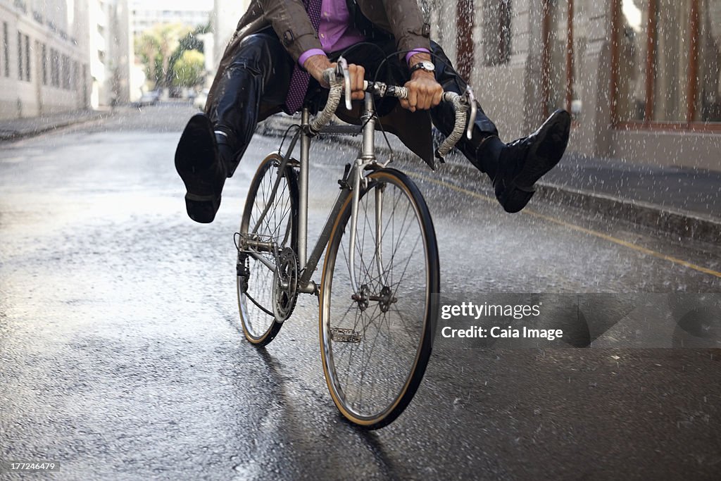 Homme d'affaires en vélo équitation avec pieds de la pluie