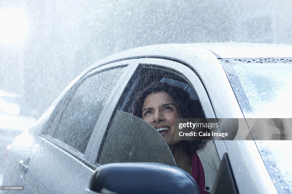 Smiling businesswoman in car looking up at rain