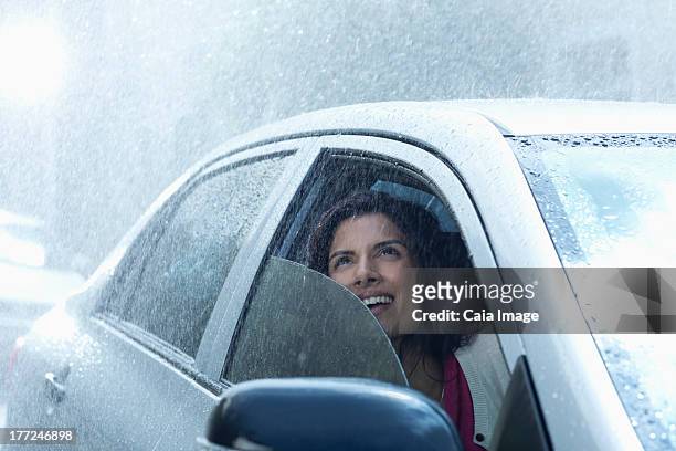 smiling businesswoman in car looking up at rain - car rain stock pictures, royalty-free photos & images