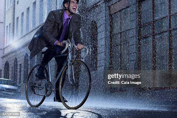 begeisterte geschäftsmann reiten fahrrad in regnerischen street - business man on bike stock-fotos und bilder