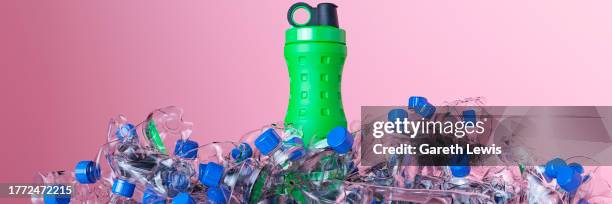 green reusable drinking bottle surround by everyday purchased water bottles 3d render - garbage pile stock illustrations