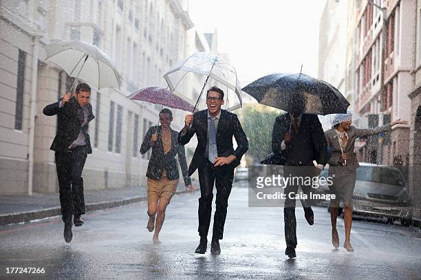 business people with umbrellas running in rainy street - businesswoman under stock pictures, royalty-free photos & images