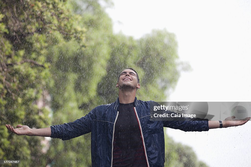 Man with arms outstretched in rain