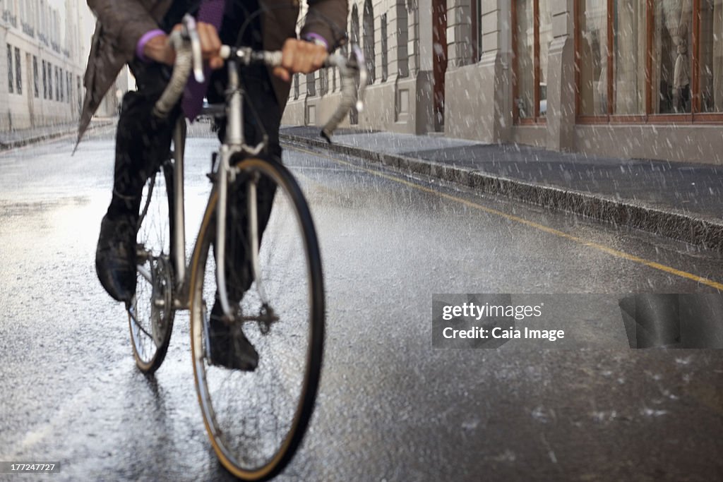 Businessman riding bicycle in rainy street