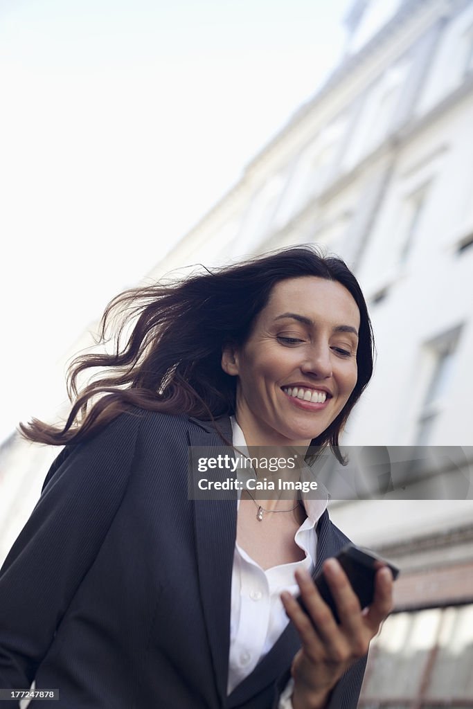 Happy businesswoman text messaging with cell phone