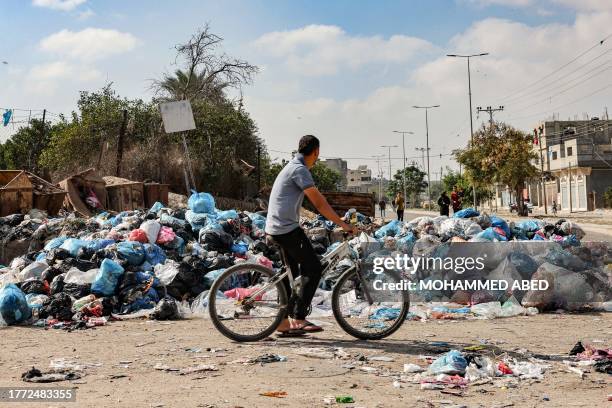 Man rides a bicycle past a pile of trash in Rafah in the southern Gaza Strip on November 9, 2023 amid continuing battles between Israel and the...