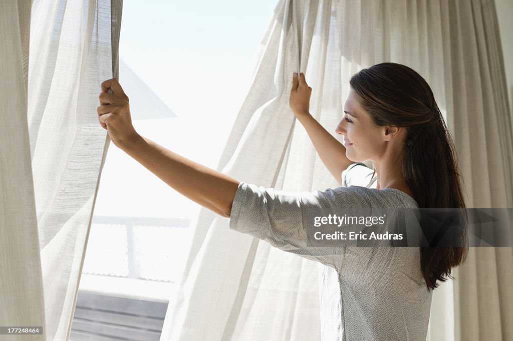 Woman opening the curtain of a window