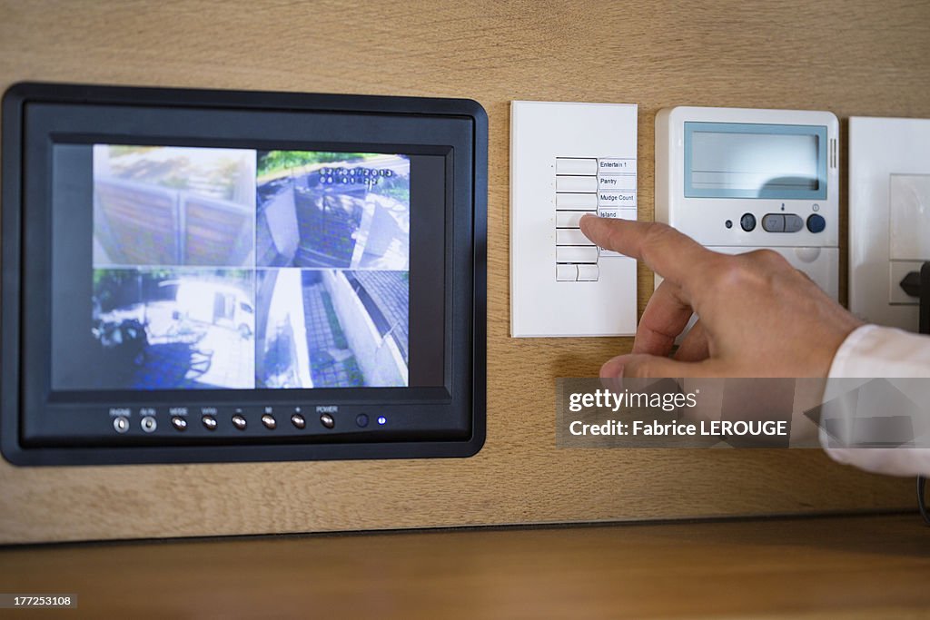 Person's hand pushing buttons for a security surveillance system at home