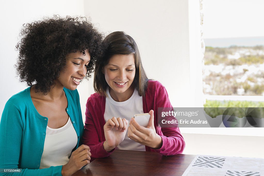 Friends using a mobile phone and smiling