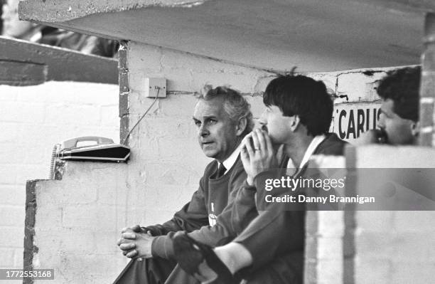 Carlisle United manager Clive Middlemass looks on from the dugout next to the dugout telephone and Peter Hampton during a Second Division match circa...