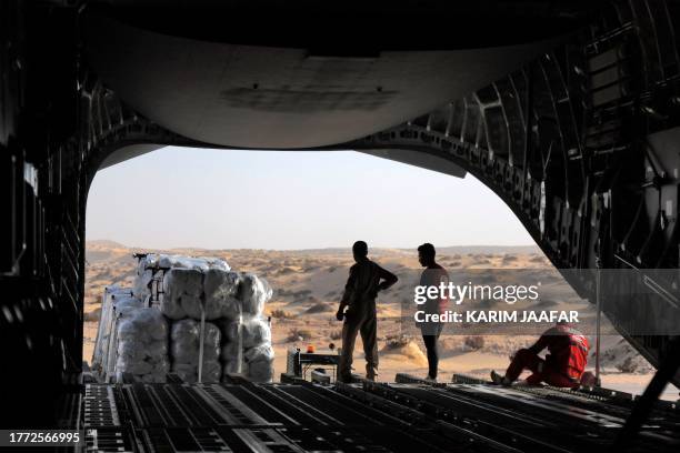 Workers unload humanitarian aid bound for the Gaza Strip off a Qatar Emiri Air Force C-17 Globemaster III military transport aircraft after landing...