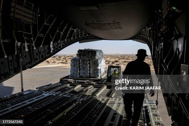 Workers unload humanitarian aid bound for the Gaza Strip off a Qatar Emiri Air Force C-17 Globemaster III military transport aircraft after landing...