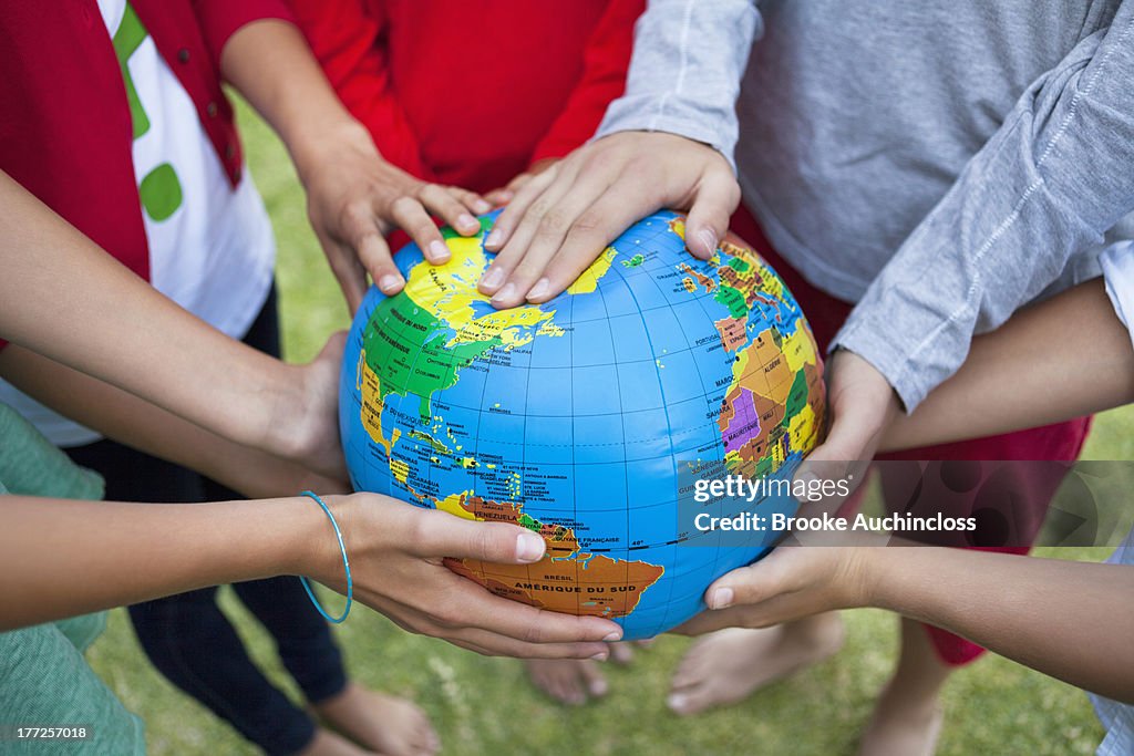 Close-up of friends holding a globe