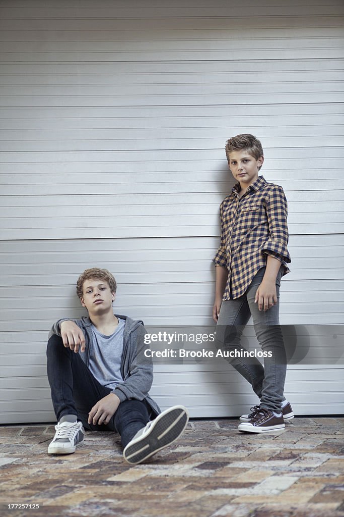 Two teenage boys leaning against a wall