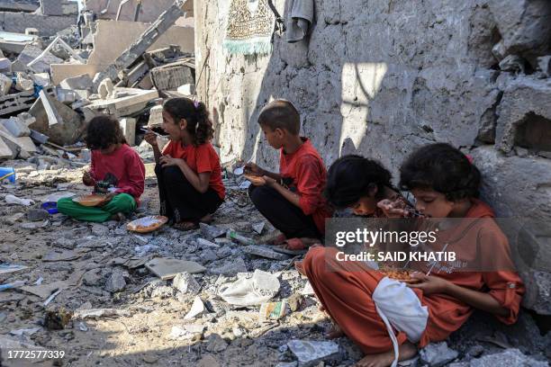 Amal al-Robayaa's children eat their meal amid the ruins of the family home destroyed in an Israeli strike in Rafah in the southern Gaza Strip, on...