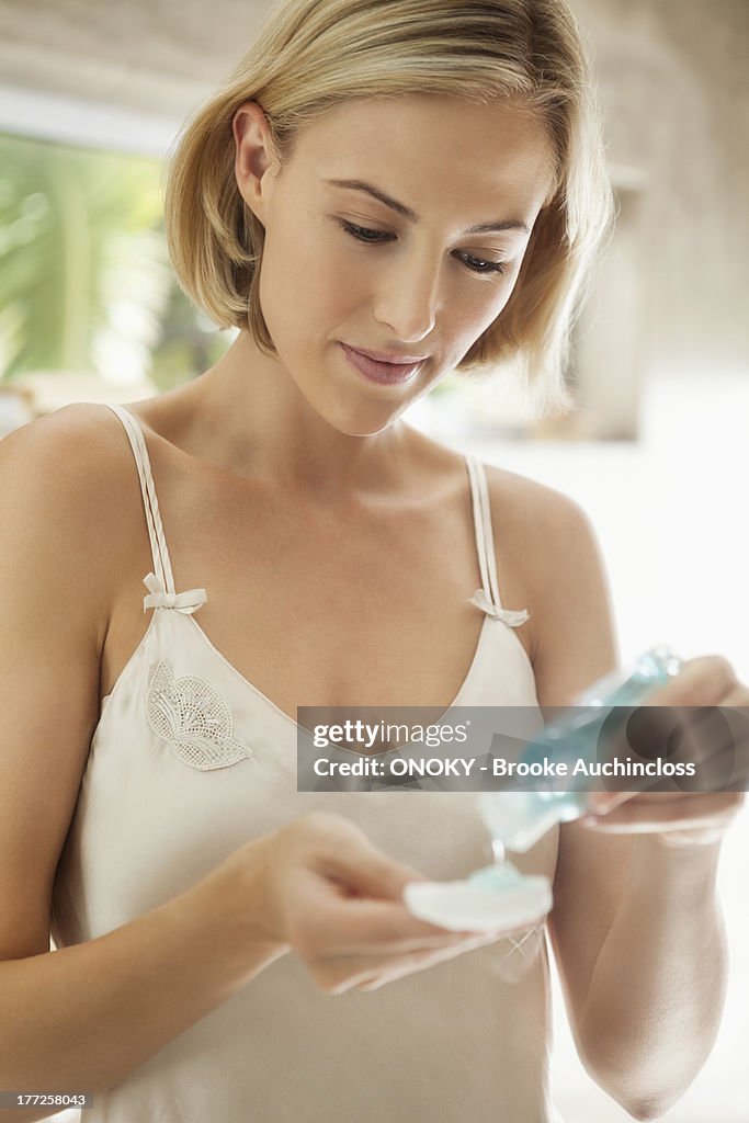 Woman pouring moisturizer on a cotton