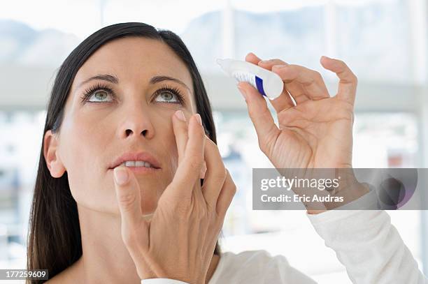 woman applying eye drops into eye - colírio imagens e fotografias de stock