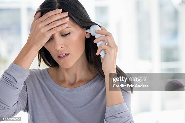 woman measuring her temperature with a digital thermometer - digital thermometer stock pictures, royalty-free photos & images