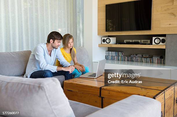 man and his daughter sitting on a couch looking at a laptop - kids rom stock pictures, royalty-free photos & images