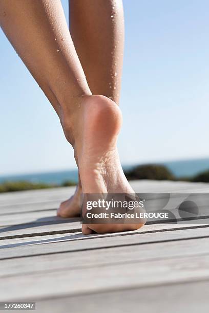 low section view of a woman walking on boardwalk on the beach - female soles stock-fotos und bilder