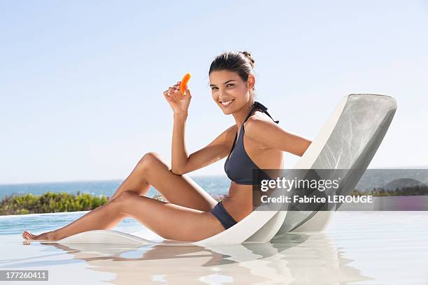 beautiful woman eating a slice of papaya - tomar el sol fotografías e imágenes de stock