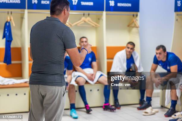 soccer trainer speaking to players in locker room - soccer locker room stock pictures, royalty-free photos & images