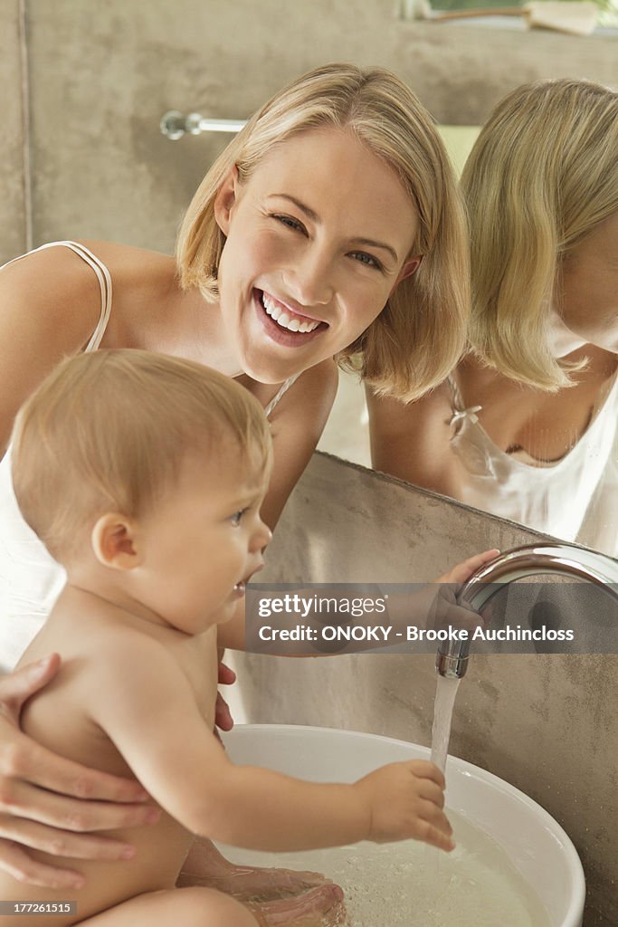 Woman giving bath to her baby in a wash bowl