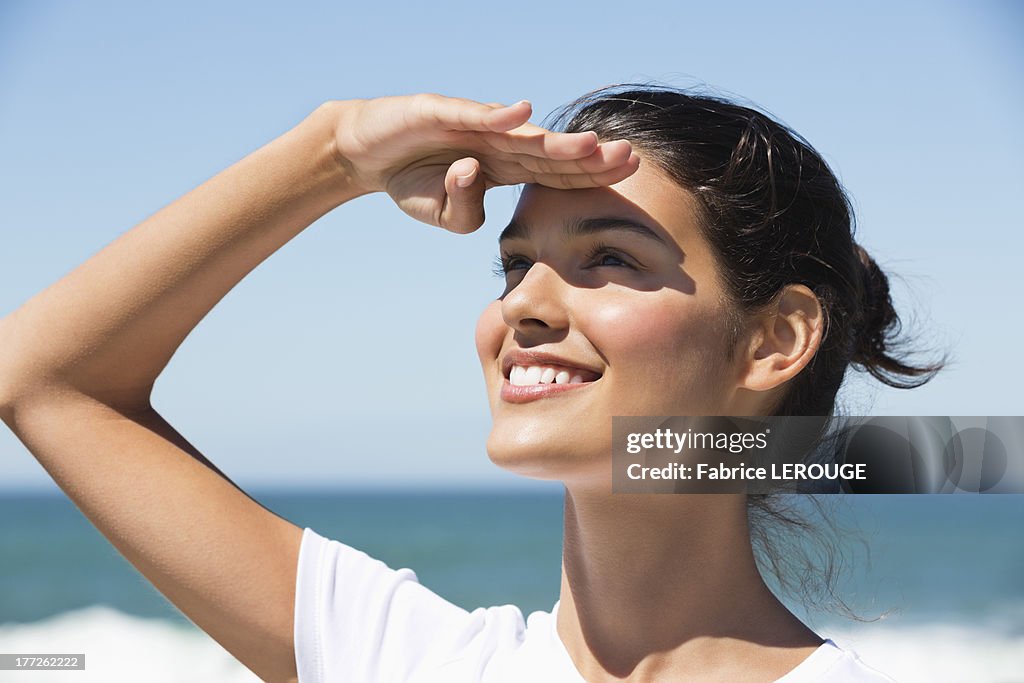 Beautiful woman shielding eyes on the beach