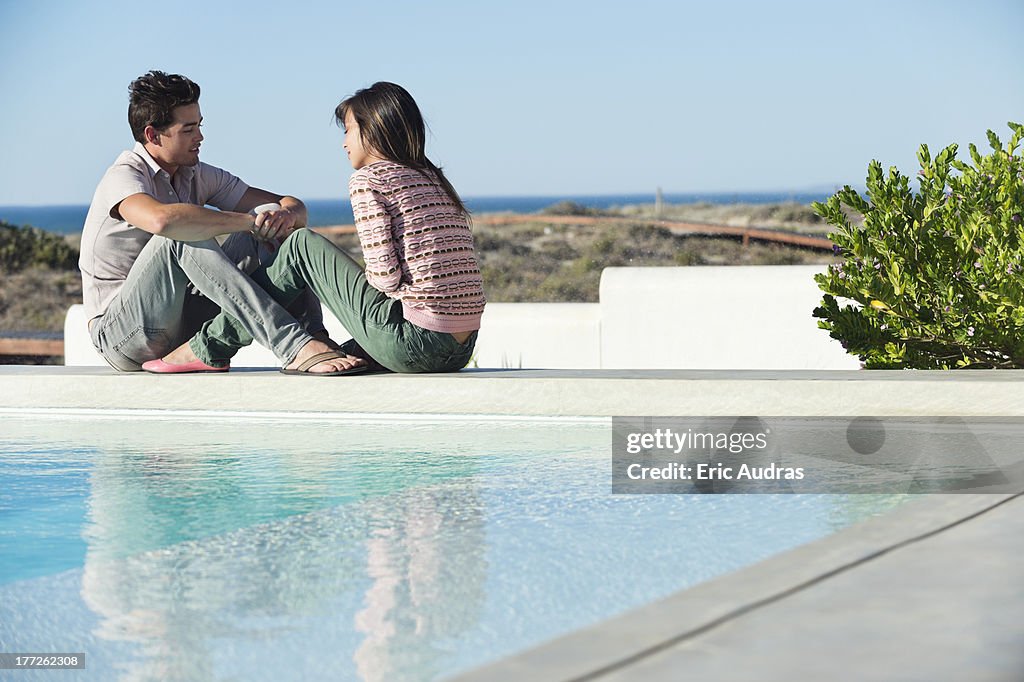 Romantic couple sitting at the poolside on the beach