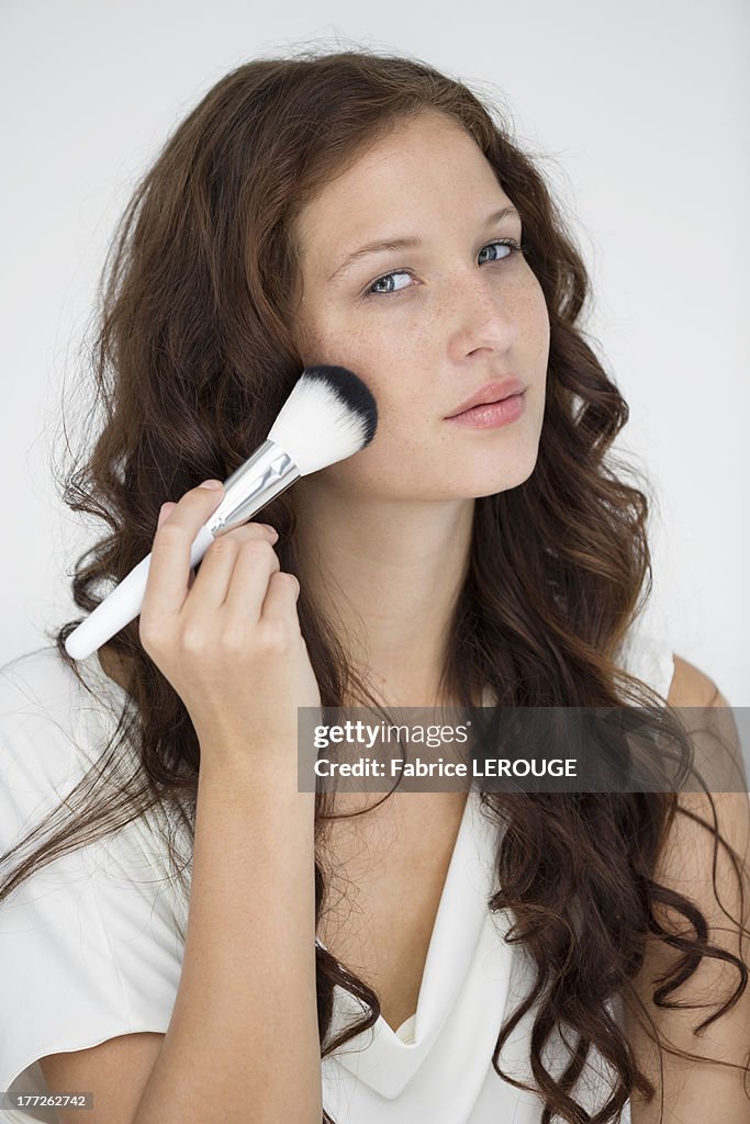 Portrait of a woman using make-up brush on face