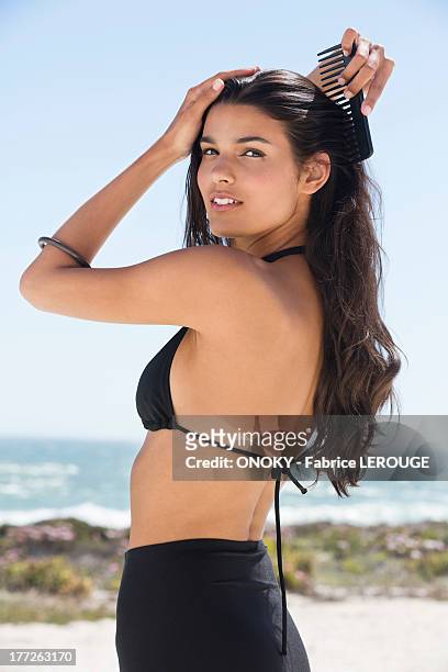 beautiful woman combing her hair on the beach - hair beauty imagens e fotografias de stock