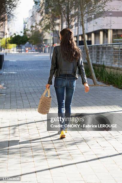 rear view of a woman walking with a handbag - jeans back stockfoto's en -beelden