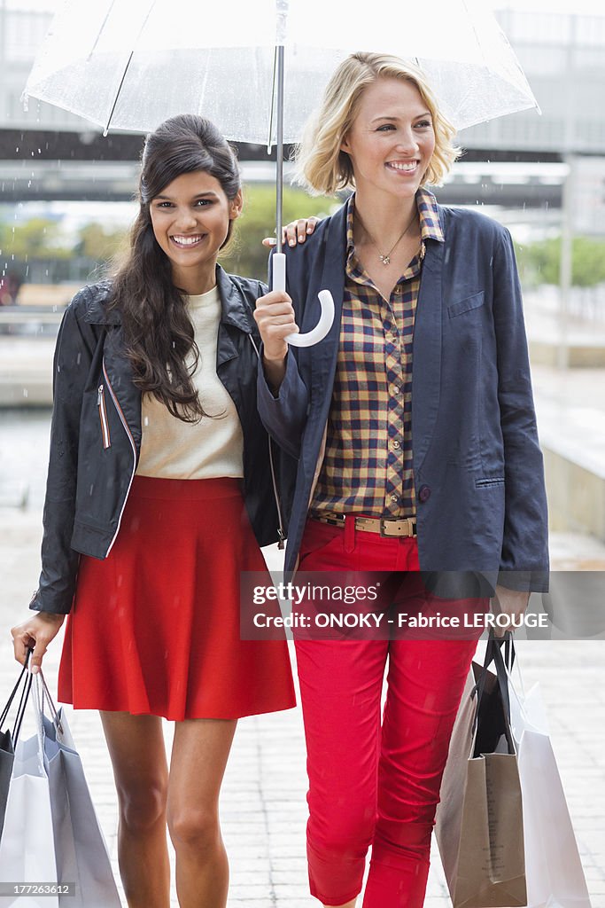 Female friends walking with shopping bags and smiling
