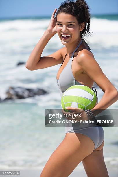 beautiful woman holding a volleyball on the beach - swimwear stock pictures, royalty-free photos & images