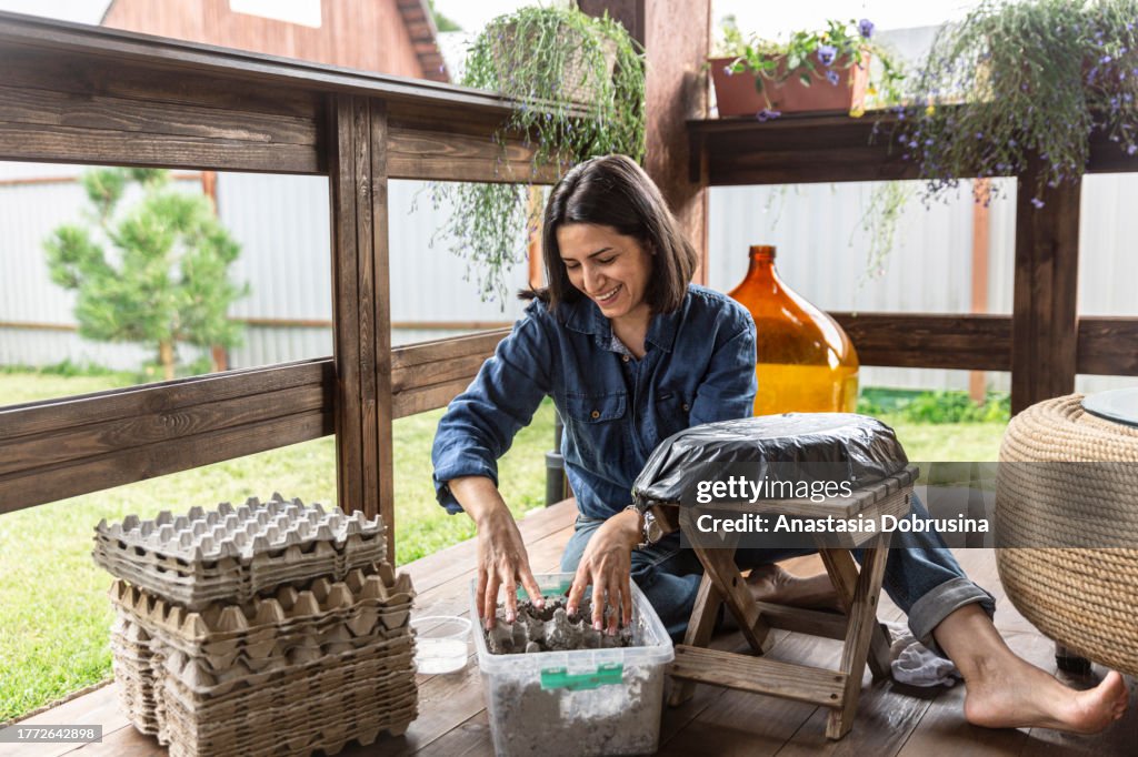 Beautiful woman making papier mache vase on the porch of wooden house.