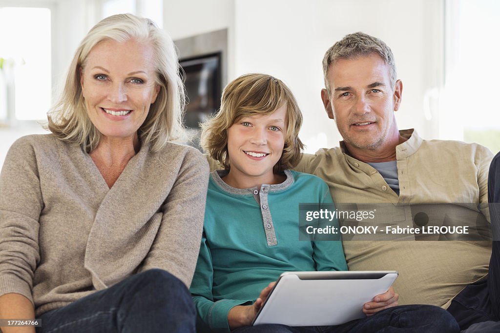 Portrait of a boy holding a digital tablet sitting with his grandparents