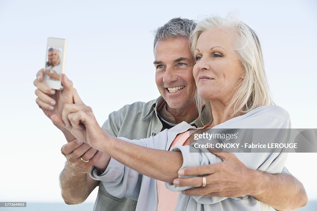 Couple taking a picture of themselves with a cell phone on the beach