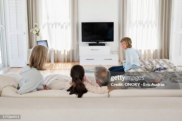 family watching television together - family watching tv from behind stock pictures, royalty-free photos & images