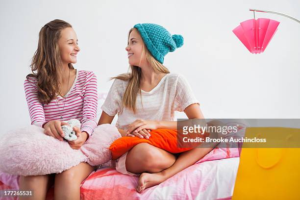 girls sitting on the bed and talking to each other at a slumber party - only girls stock pictures, royalty-free photos & images