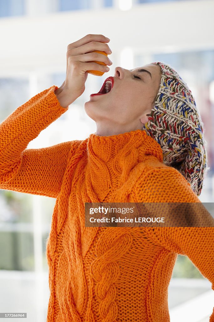 Woman squeezing juice from an orange into her mouth